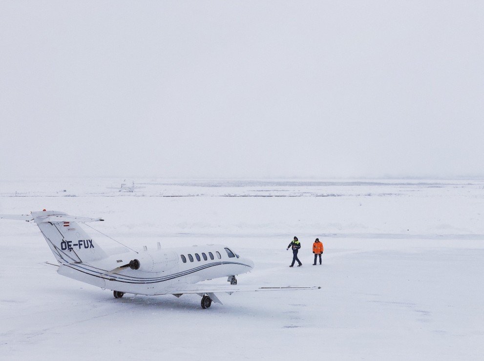 Two people walk back to a small charter plane that has landed in a snow covered landscape to travel back to the mainland.