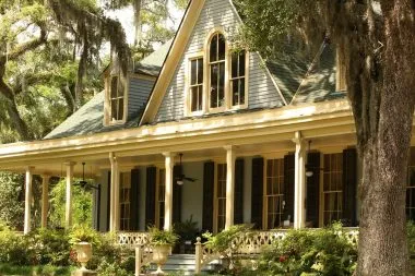 Southern plantation home with spanish moss and trees surrounding the front porch.